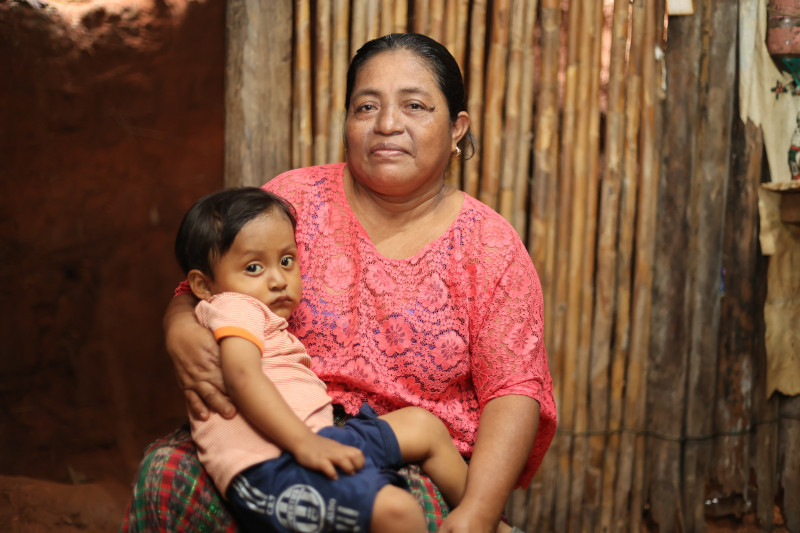 Luisa sostiene en sus brazos a su nieto Brian, quien se recupera de la desnutrición, gracias a los alimentos nutritivos que ahora pueden comprar y las recomendaciones de nutrición e higiene adquiridas a través de un programa de CRS. Foto por Allison Matus/CRS. 