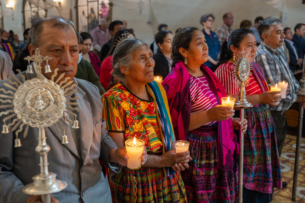 Feligreses indígenas con trajes tradicionalesparticipan en la misa en la Iglesia San Juan Bautista, en Quetzaltenango, Guatemala, mostrando la riqueza de su cultura y devoción.