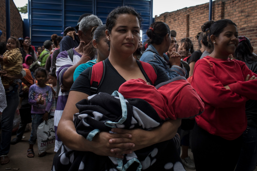 Una madre sostiene a su bebé envuelto en una manta mientras espera junto a otros inmigrantes venezolanos en un albergue en Cúcuta, Colombia.