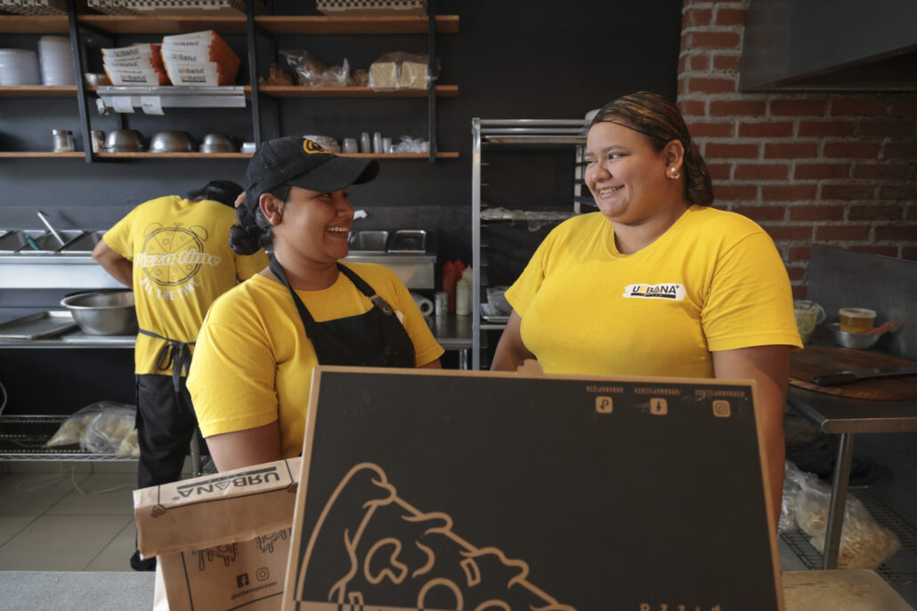 Maydeline tiene a cargo un personal de ocho personas en la pizzería. Aquí comparte con una de sus trabajadoras.